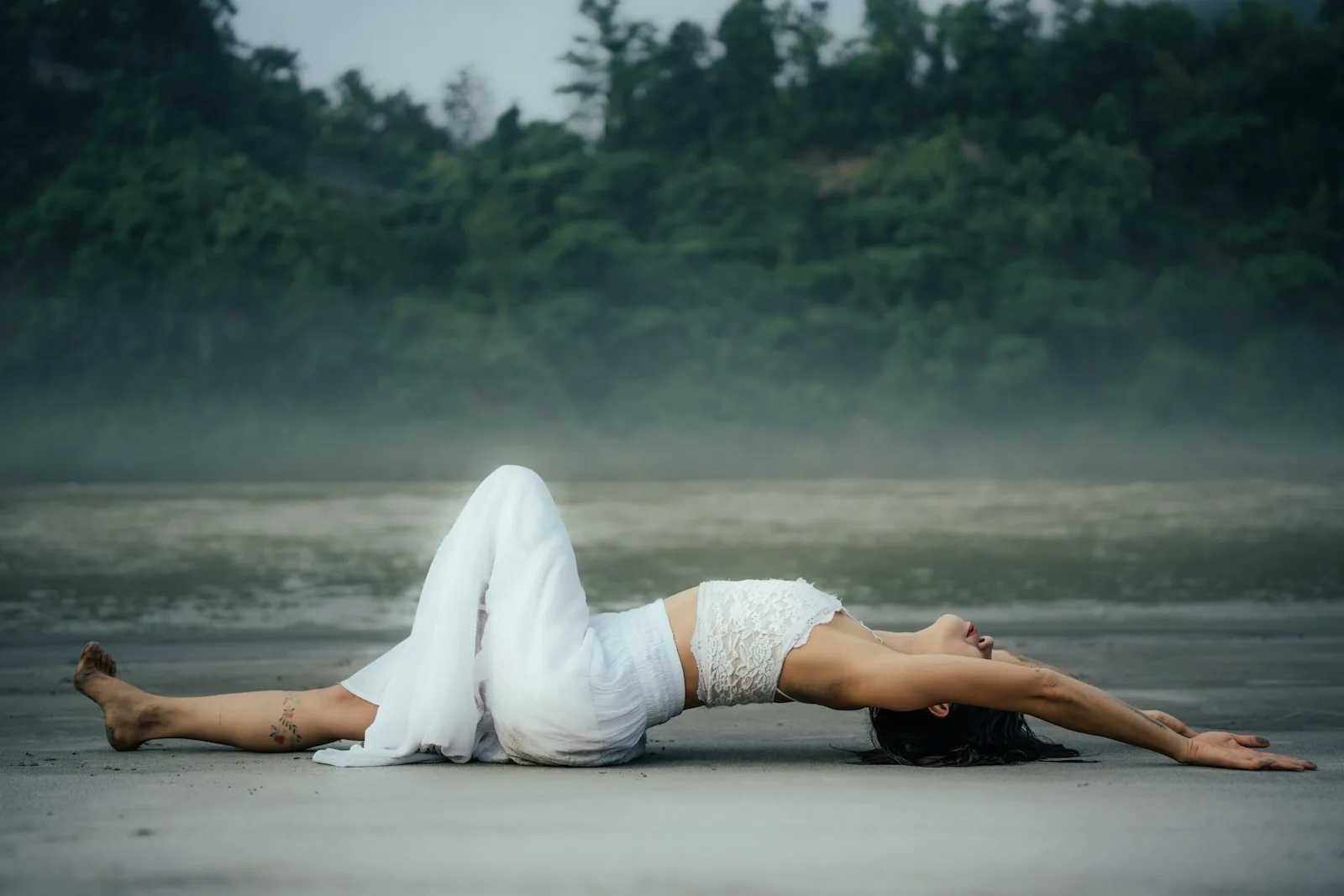 A woman laying on her back on the beach